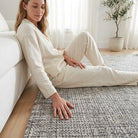 Woman sitting on a textured rug in a bright living room