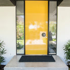 Yellow door with glass panels on a white wall, featuring a doormat.