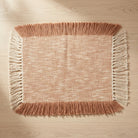 Textured placemat with fringes on a wooden surface