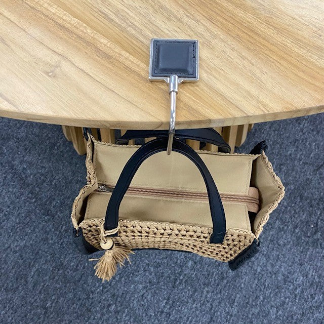 Beige bag with black handle and trim on a wooden table