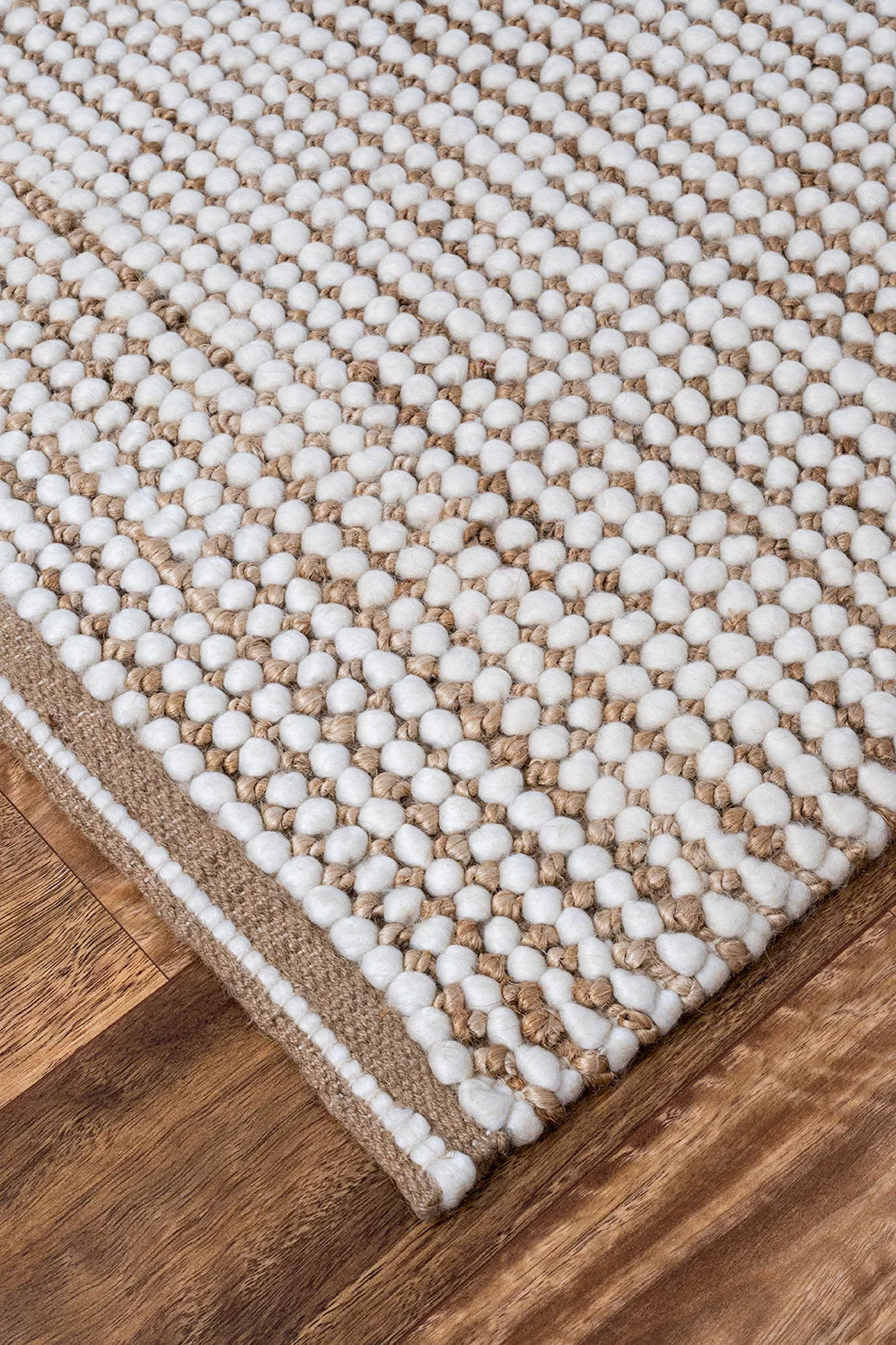 Showcasing the unique blend of wool and jute, this image highlights the rug's intricate texture and the interplay of natural and white colors, emphasising its rustic yet refined look.
