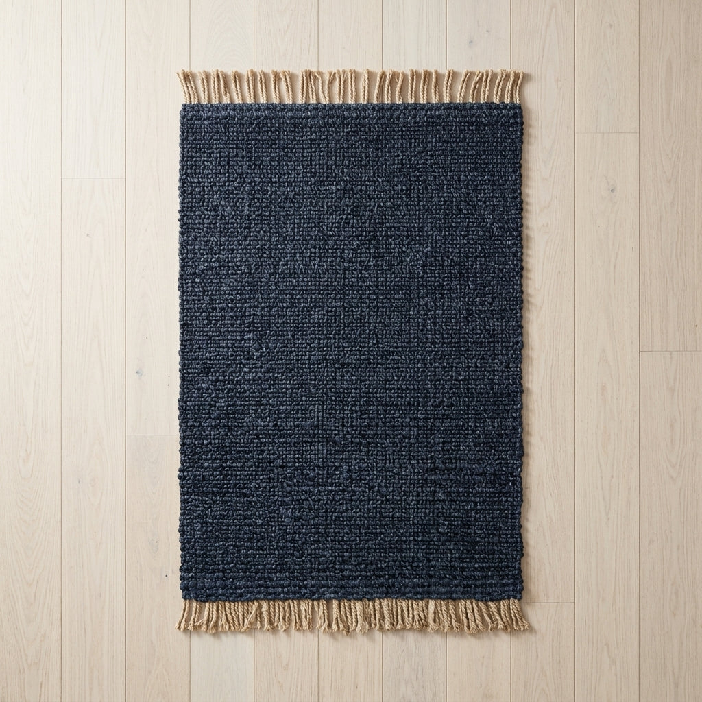 Navy blue rug with beige fringe on a light wood floor