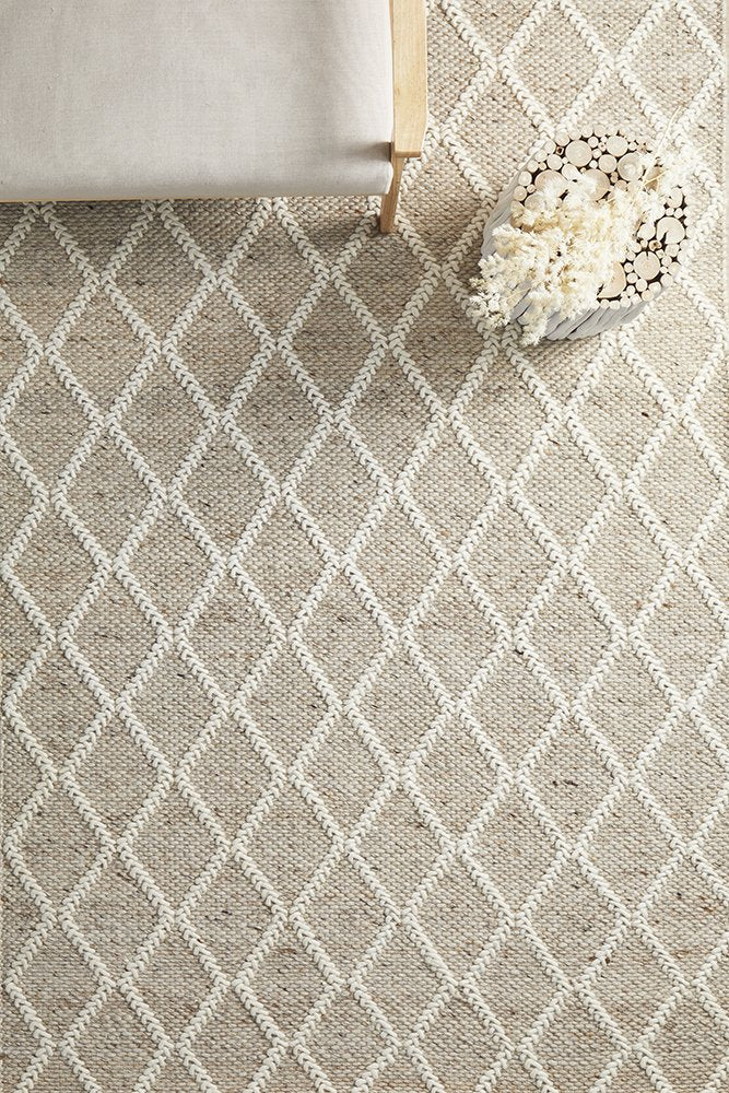 Beige and white diamond patterned rug with a wooden stool and decorative basket on top.