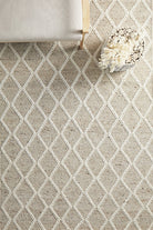 Beige and white diamond patterned rug with a wooden stool and decorative basket on top.