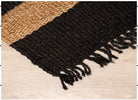 Black and brown woven rug with fringe on a light background
