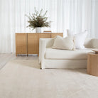 Modern living room with a beige sofa, side table, and decorative cabinet.