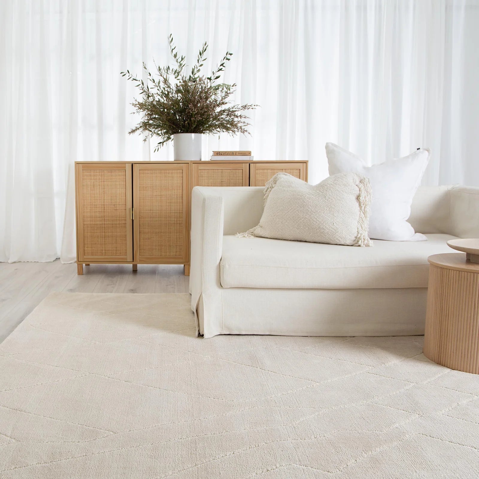 Modern living room with a beige sofa, side table, and decorative cabinet.