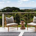 Two wooden chairs with cushions on a deck overlooking a scenic landscape.