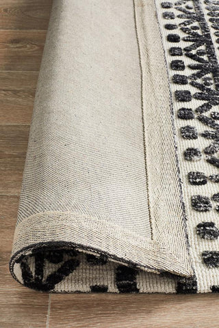 Noosa Rug's Levi Rug in Ivory Black rolled up, demonstrating its flexibility and dense pile, suitable for various home settings.