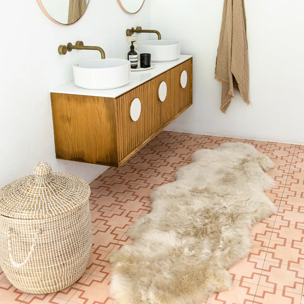 Bathroom with wooden vanity, white sinks, and patterned pink floor.