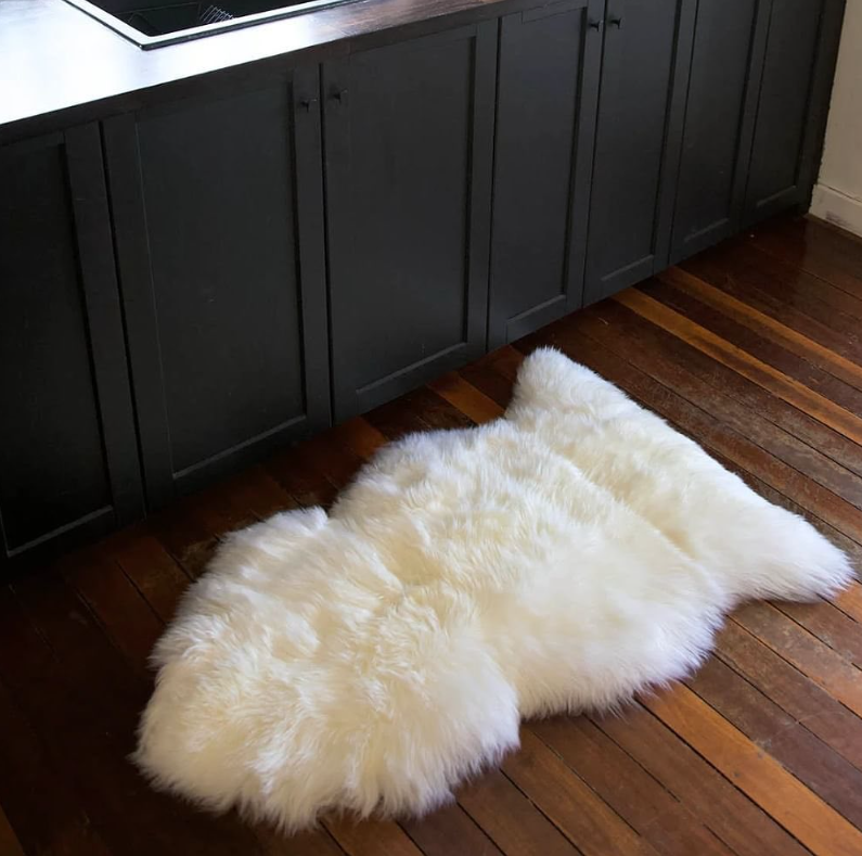 White New Zealand wool sheepskin single rug on a wooden floor in a kitchen setting