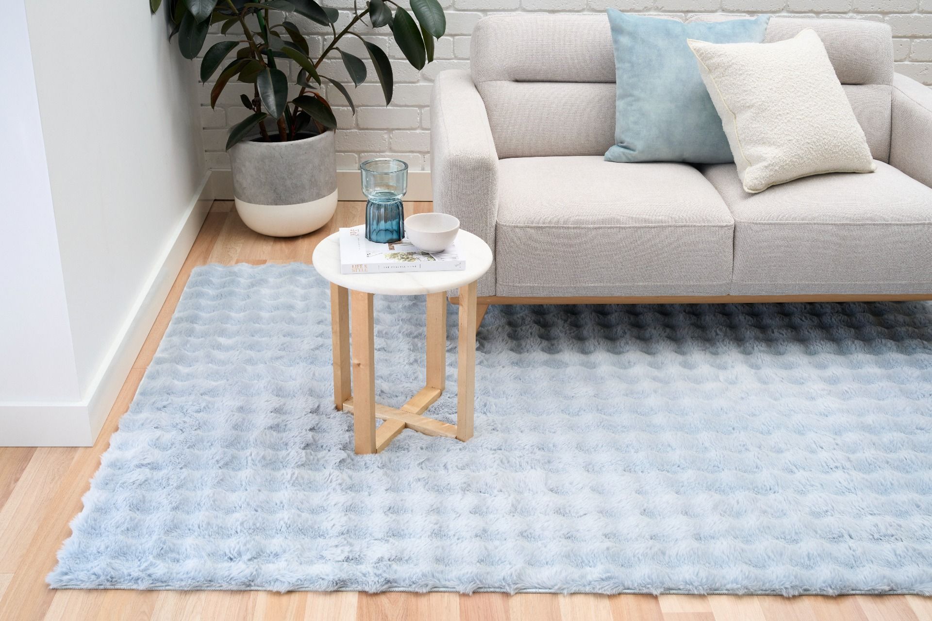 Living room with a light blue rug, gray sofa, and small round table.