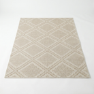 A rectangular area rug with a textured geometric diamond pattern in beige and light brown, shown from a top-down perspective on a white background.