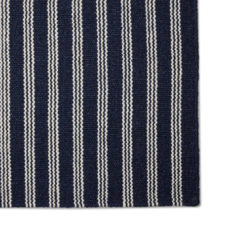 Navy blue and white striped rug corner on a white background