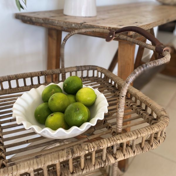 Wicker tray with a bowl of limes on a wooden table