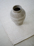 Gray textured vase on a textured white rug