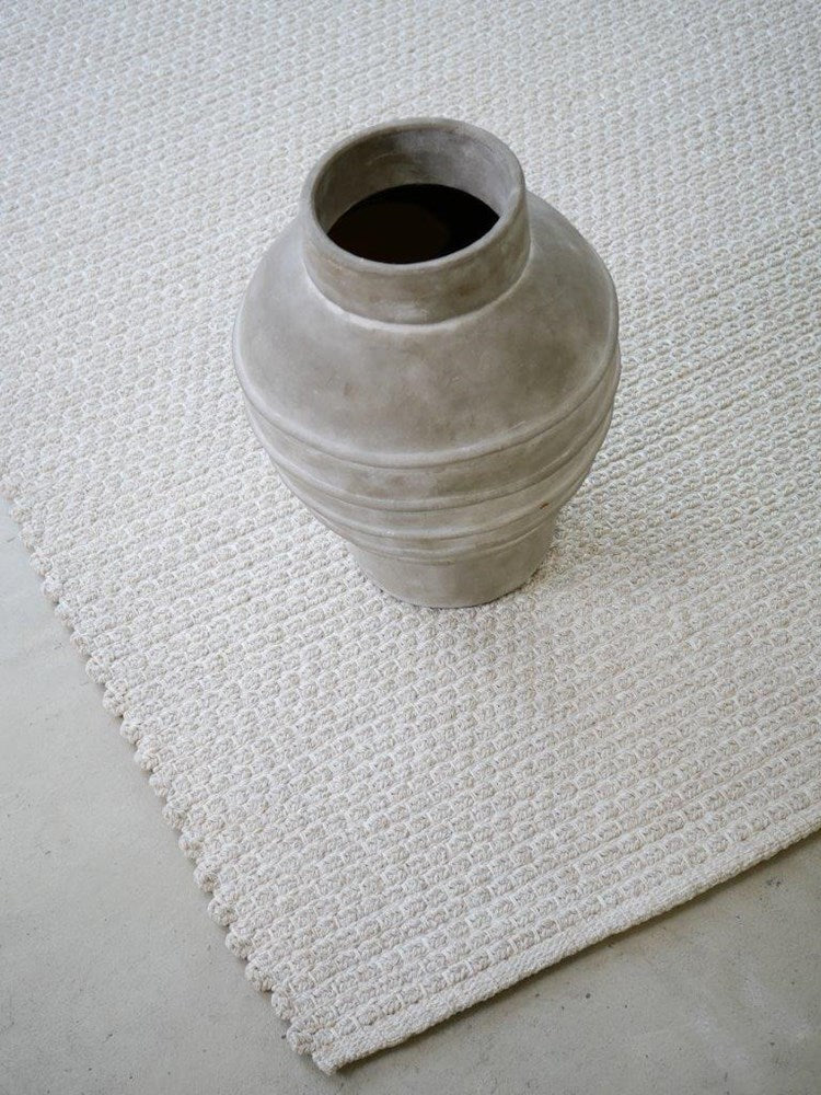 Gray textured vase on a textured white rug
