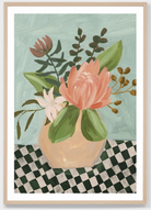 A framed art print featuring a still life painting of a pink protea flower in a beige vase, surrounded by green leaves, set against a light blue-green background with a black and white checkered surface.
