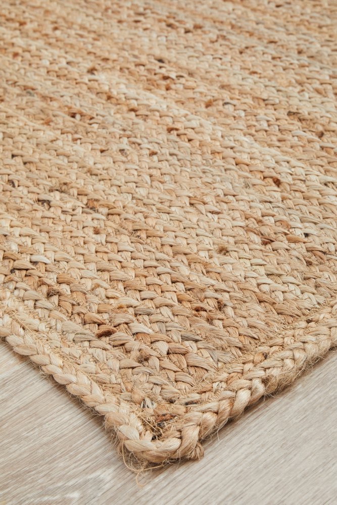 Close-up of a woven natural fiber rug on a wooden floor.