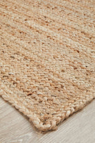 Close-up of a woven natural fiber rug on a wooden floor.