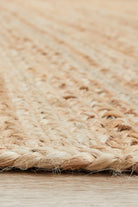 Close-up of a woven natural fiber rug on a wooden floor.