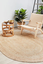 Round jute rug in a room with a wooden chair, small table, and potted plant.