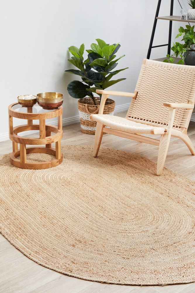 Round jute rug in a room with a wooden chair, small table, and potted plant.