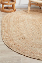 Round jute rug on a wooden floor with wooden furniture.