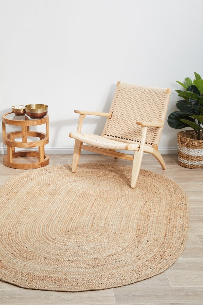 Round jute rug in a room with a wicker chair, small table, and plant.