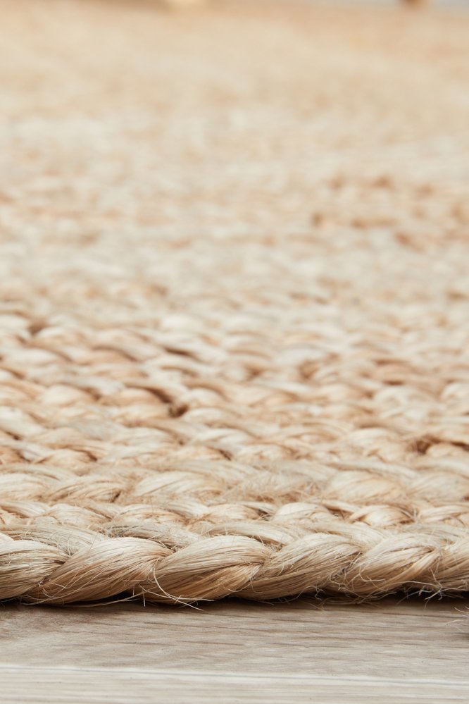 Close-up of a woven natural fiber rug on a wooden floor.