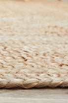 Close-up of a woven natural fiber rug on a wooden floor.