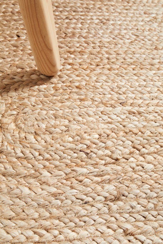 Close-up of a woven jute rug with a wooden chair leg.