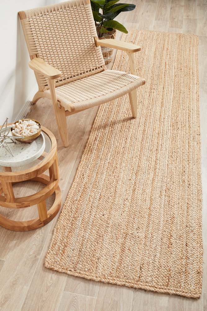 Woven natural rug on a wooden floor with a wicker chair and side table.