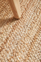 Close-up of textured beige carpet with a wooden furniture leg.