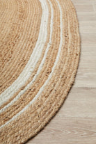 Round braided rug with beige and white stripes on a wooden floor