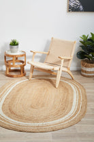 Woven chair and round jute rug in a room with plants and a side table.