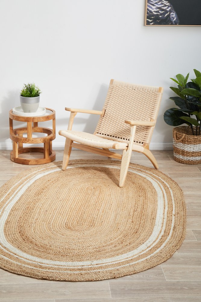 Woven chair and round jute rug in a room with plants and a side table.