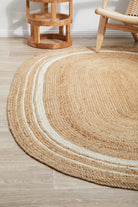 Round jute rug on a wooden floor with a chair and side table in the background.