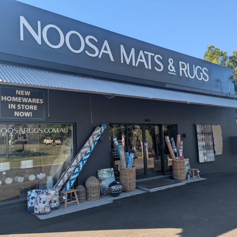Storefront of Noosa Mats & Rugs with various home decor items displayed outside.