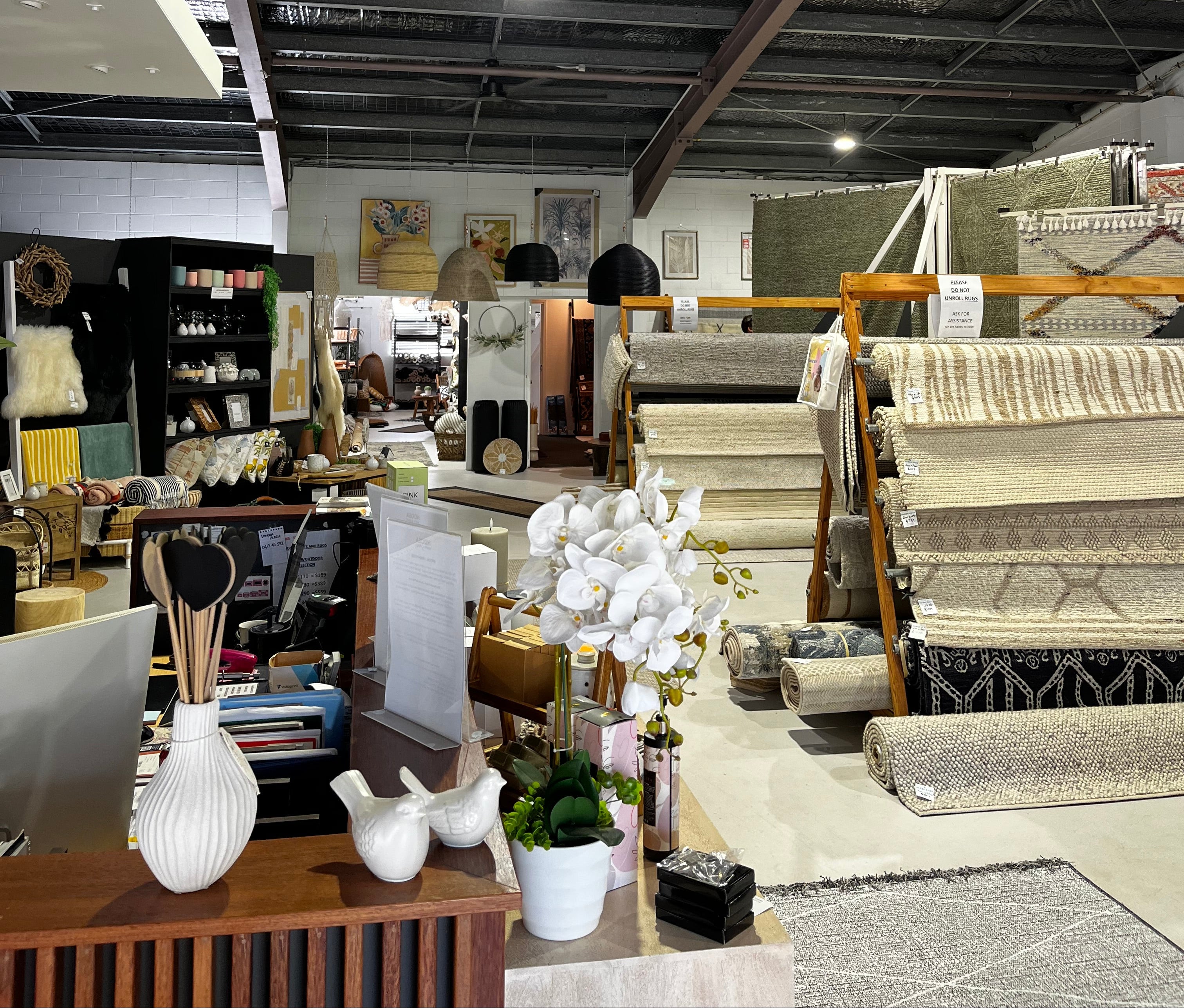 Interior of a store with shelves displaying various items, including fabric samples and decor elements.