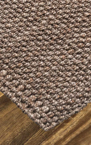 Close-up of a textured brown carpet corner on a wooden floor