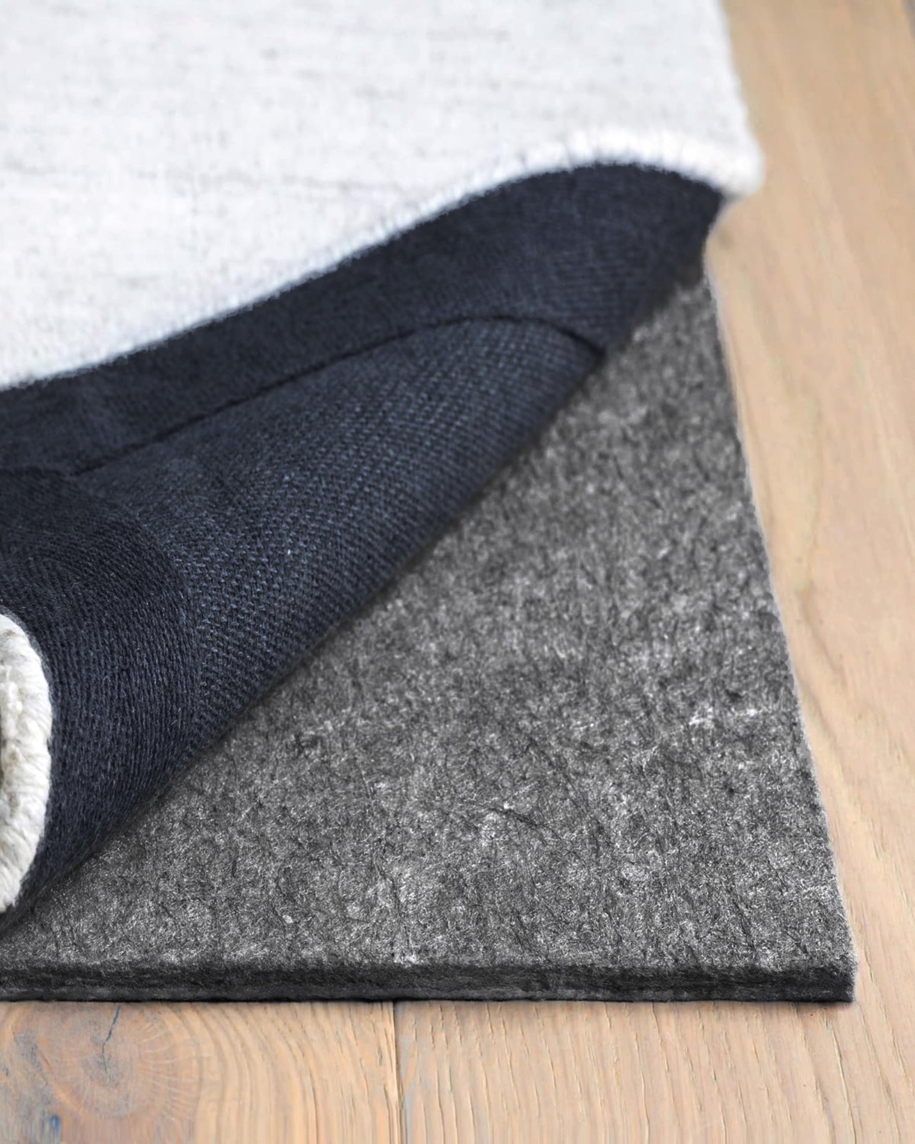 Close-up of a rug with a textured pad on a wooden floor