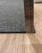 Gray carpet sample with a ruler for size reference on a wooden floor.