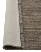 Close-up of a textured rug corner with a neutral color palette.