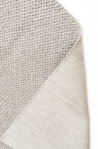 Close-up of a textured gray rug corner on a white background