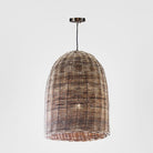 A dome-shaped woven pendant light shade made from natural brown and beige wicker, suspended from a dark metal ceiling canopy against a light gray background.