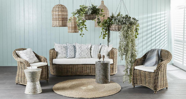 Outdoor furniture set with wicker chairs, sofa, and side table on a wooden deck.