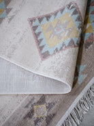 Close-up of a textured rug with geometric patterns and fringes.