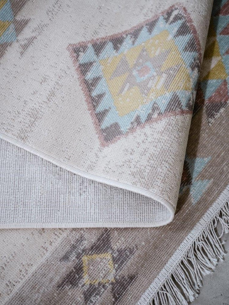 Close-up of a textured rug with geometric patterns and fringes.