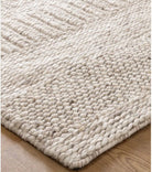 A close-up image of a beige wool and nylon blend rug with a textured pattern.